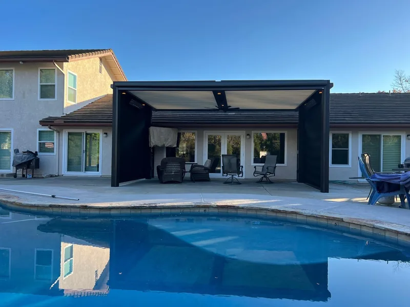 Attached Four Seasons louvered roof with black frame, latte blades and drop-down side screens, seen across the pool