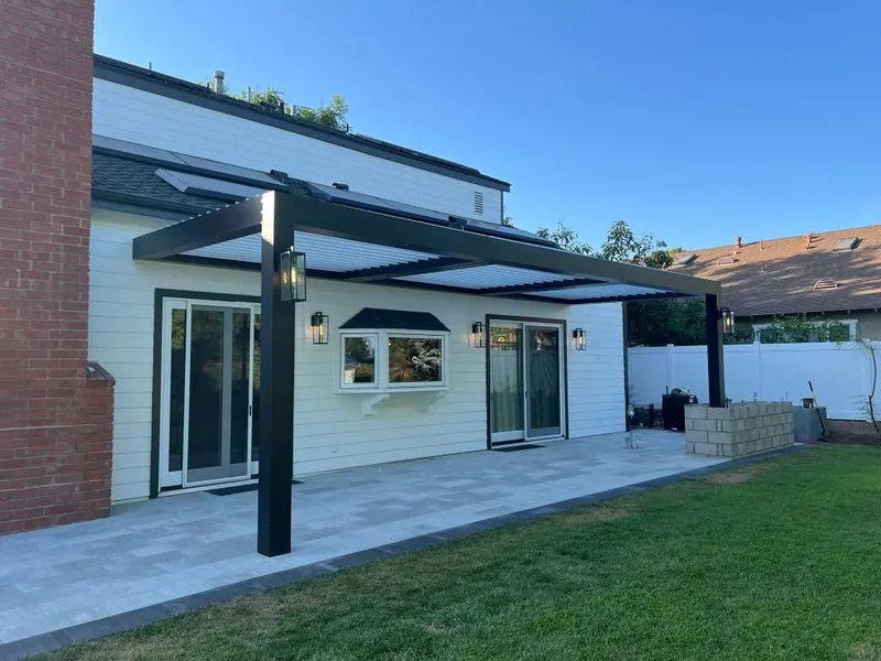 Attached Four Seasons louvered roof with black frame and white blades, lantern lights mounted on the posts