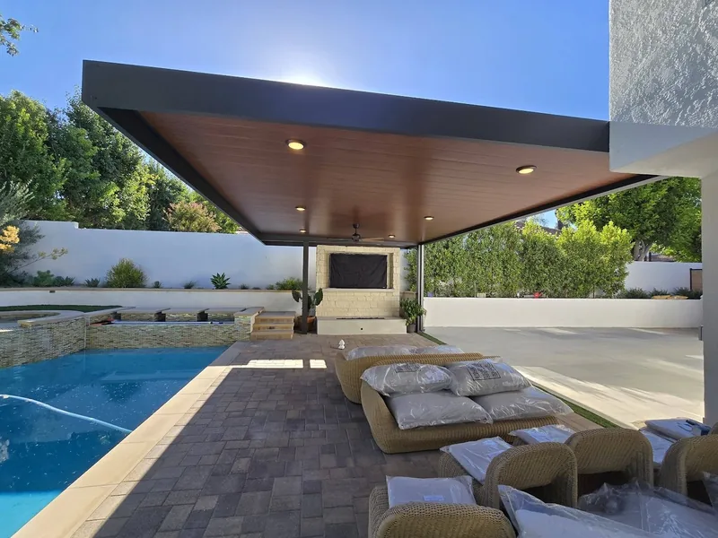 Large-overhang 4K frame in espresso with Western Cedar 3-inch insulated panels and six recessed lights, over a poolside lounge
