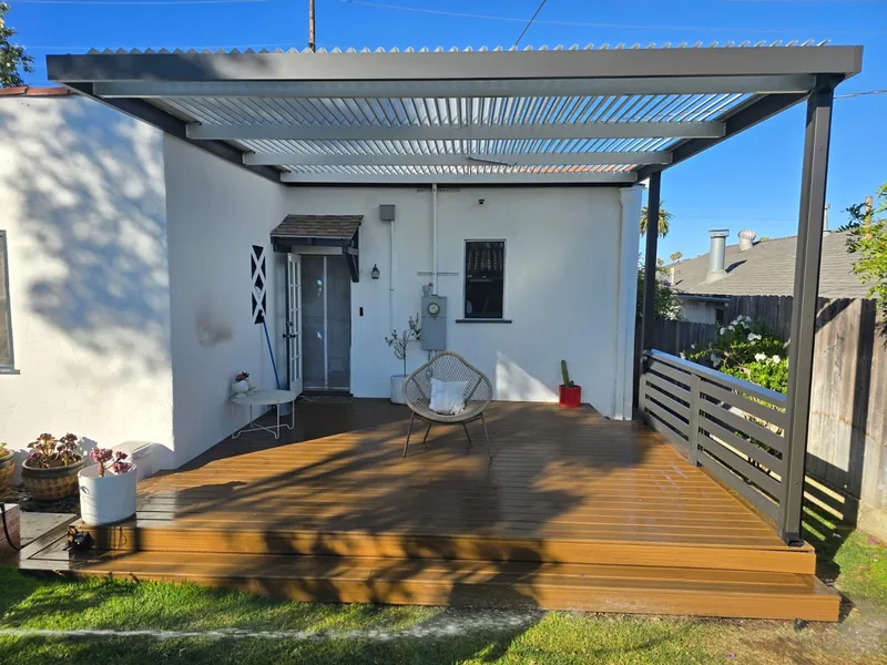 Attached espresso 4K frame with white Solara adjustable louvers over a wooden deck, with 1x4 4K railing